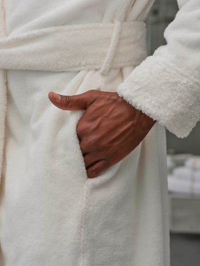Abyss & Habidecor COMFY 500gr: Valge froteest hommikumantel inimese seljas lähivaates, käsi pistetud küljetaskusse