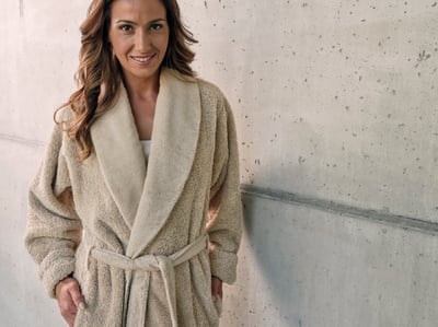 Abyss & Habidecor SUPER PILE 700gr: Beež froteest hommikumantel vöö ja laia sallkraega naise seljas betoonseina taustal