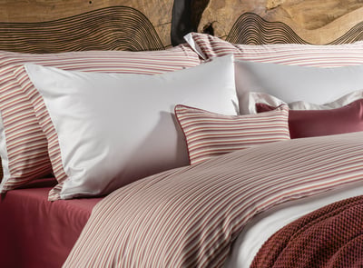 Celso de Lemos BAYA pillowcase: White flanged pillowcases and striped pillows in front of a wooden headboard