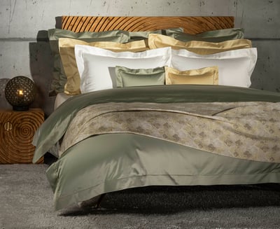Celso de Lemos BOURDON duvet cover: A bed with an olive-green duvet cover and green, gold and white pillowcases in front of a wooden headboard
