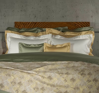 Celso de Lemos BOURDON duvet cover: Green, gold and white pillowcases in front of a carved wooden headboard, with a gold patterned coverlet in front