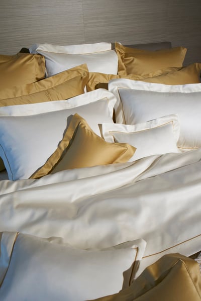 Celso de Lemos BOURDON duvet cover: Gold and white pillowcases and a sheet on a bed