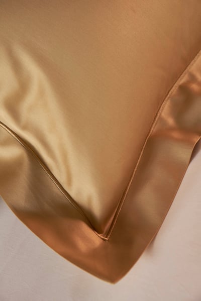 Celso de Lemos BOURDON duvet cover: Close-up of the corner of a gold pillowcase on a white sheet